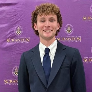 Young man with curly hair in a dark blue business suit.
