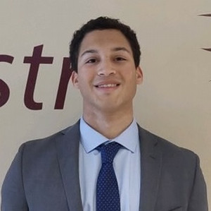 Young man with short dark hair, dressed in gray business suit.