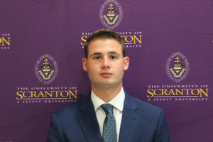 Young man in blue suit in front of purple background